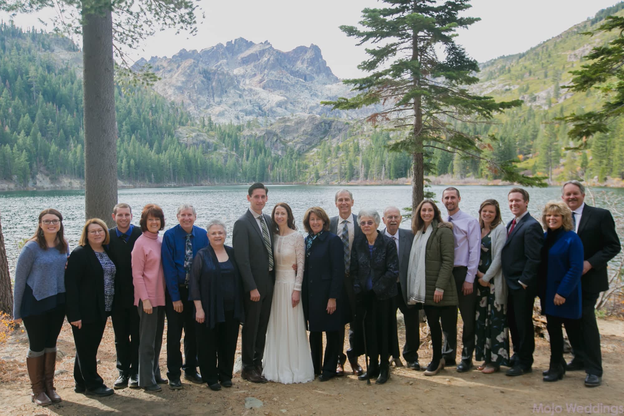 A portrait of the bride and groom and all their guests in front of the lake and mountains.